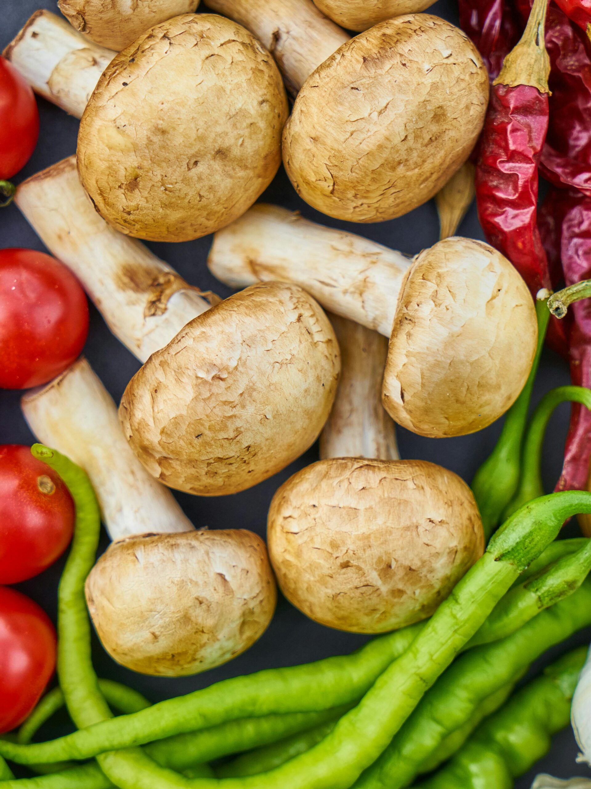 A vibrant assortment of fresh vegetables and mushrooms arranged in a flat lay.